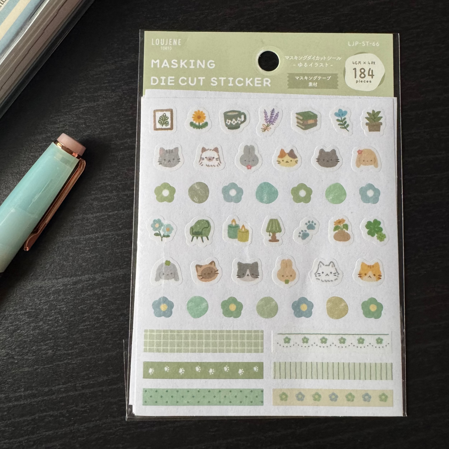 Packaging of a sheet of die-cut stickers with various designs on a dark surface.